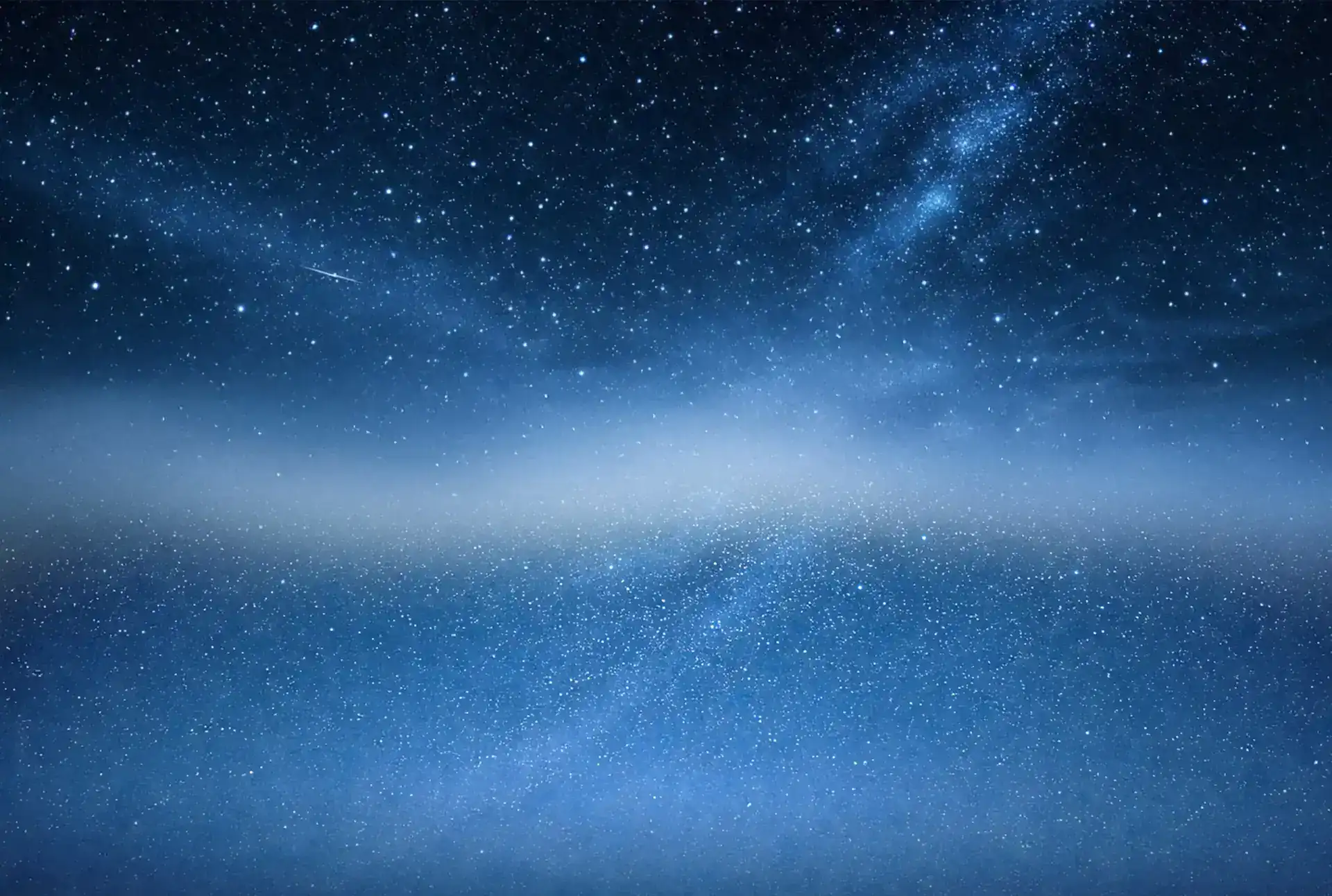 Night sky with stars and Milky Way galaxy over a calm ocean.