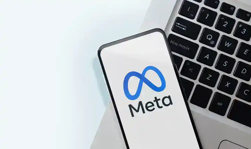 Meta logo on smartphone with keyboard, digital marketing concept.