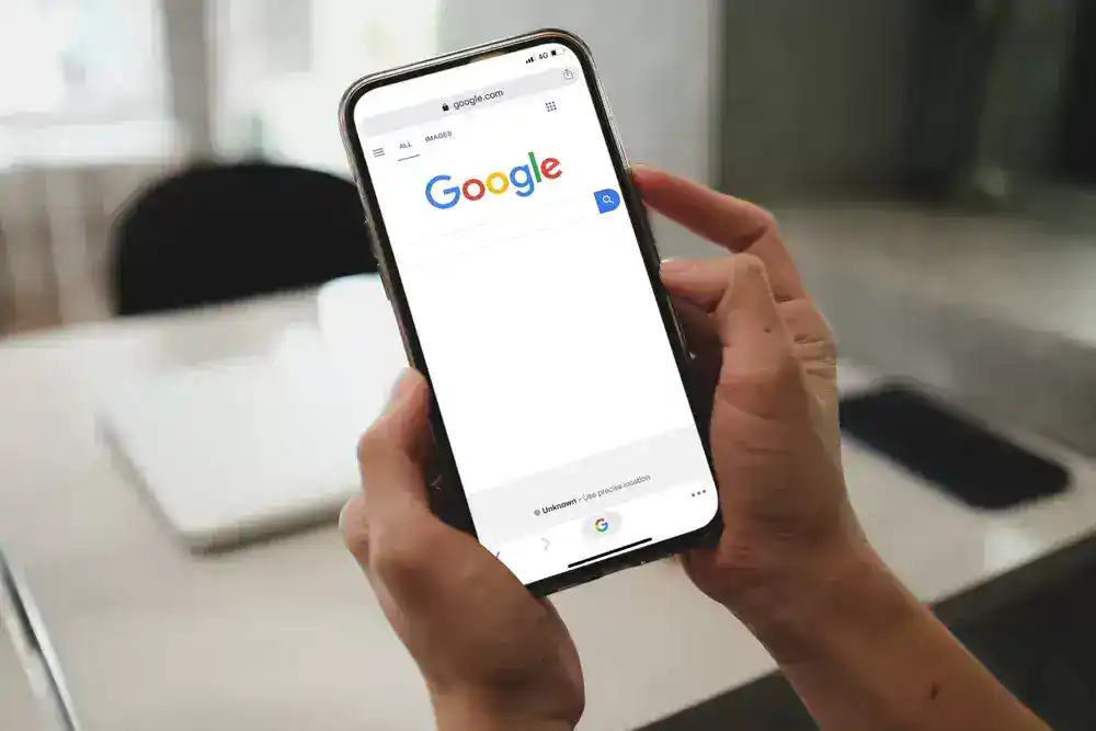 Person holding a smartphone displaying Google search page, illustrating AI-driven search advertising.